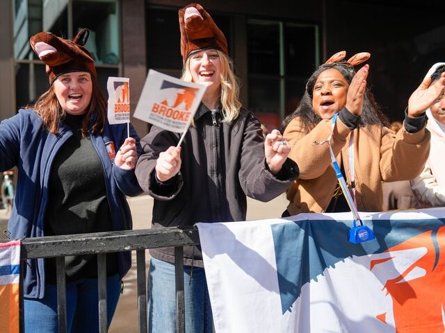 Brooke fundraising team members cheer on runners at a marathon, while wearing funny fake horse hats and donkey ears