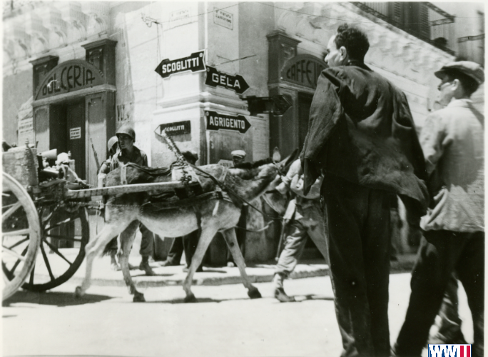 US soldiers move supplies with a donkey-drawn cart to the front line via a city street in Sicily, 1943.