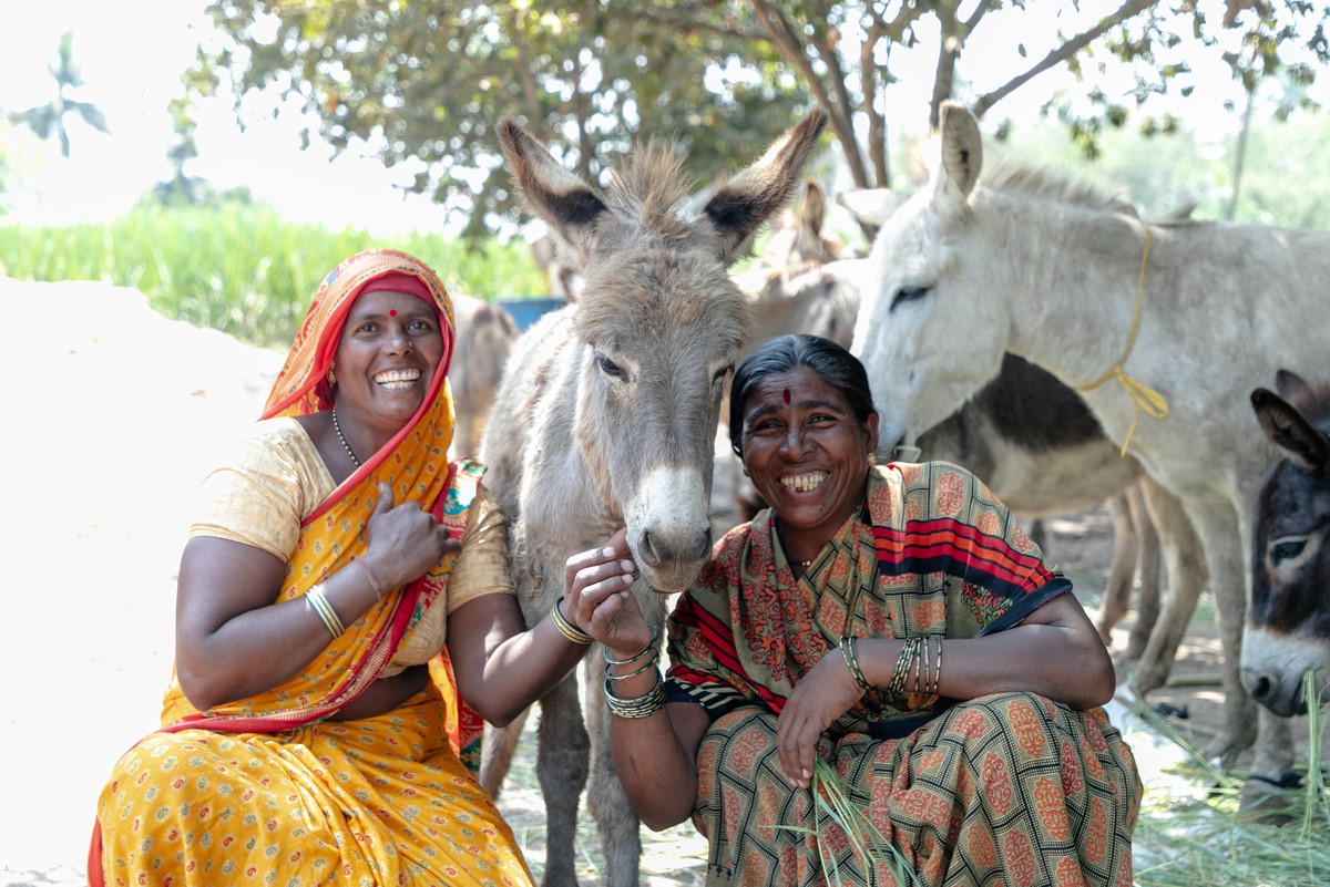 Women smiling next to donkey in Indian brick kiln