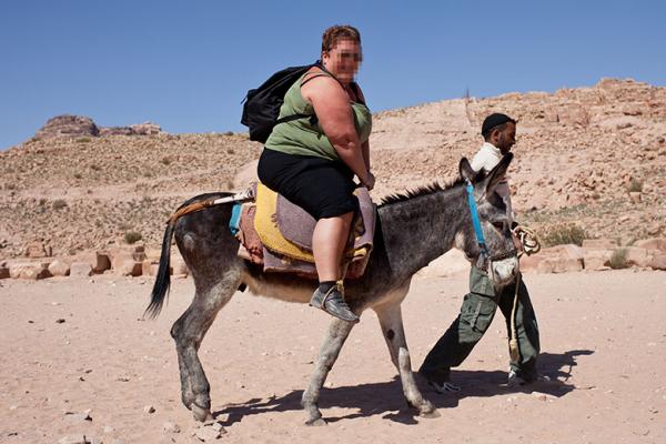 A large tourist on a donkey A large tourist on a donkey