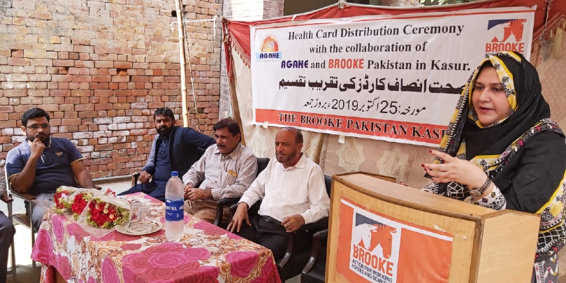 Sana giving a speech to community members in Pakistan on how government services can uplift communities through linkages with government schemes and other organisations Woman in Pakistan speaking to community members