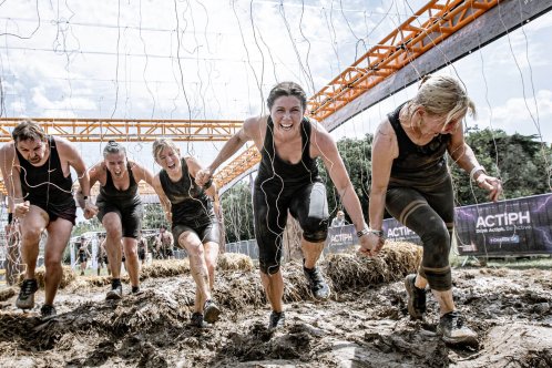 fundraisers crawling through mud obstacle course