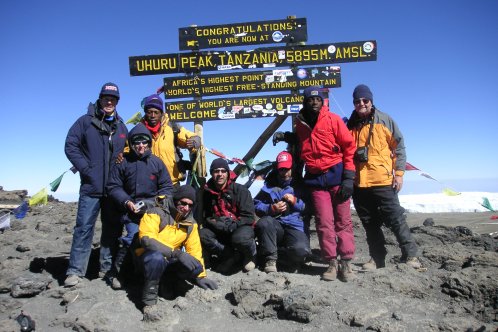 A group of people stand at the summit of Kilimanjaro