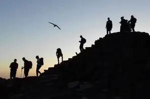 Hikers silhouetted at sunrise on Yr Wyddfa