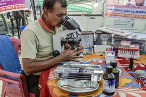 Man looking through microscope at samples of equine blood.
