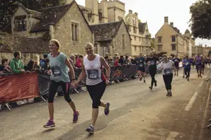 Two women run down a street