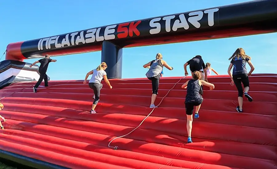 Fundraisers climbing red inflatable obstacle mountain