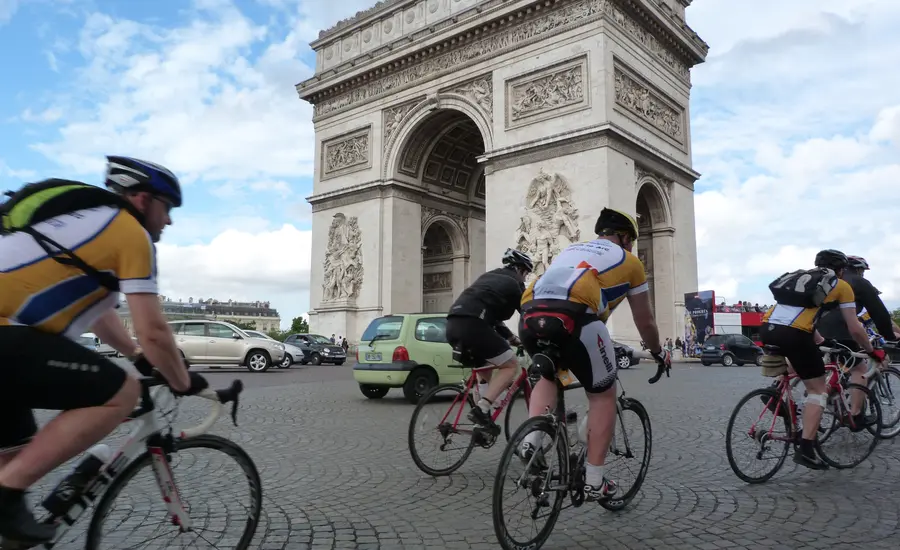 Cyclists pass the Arc de Triomphe
