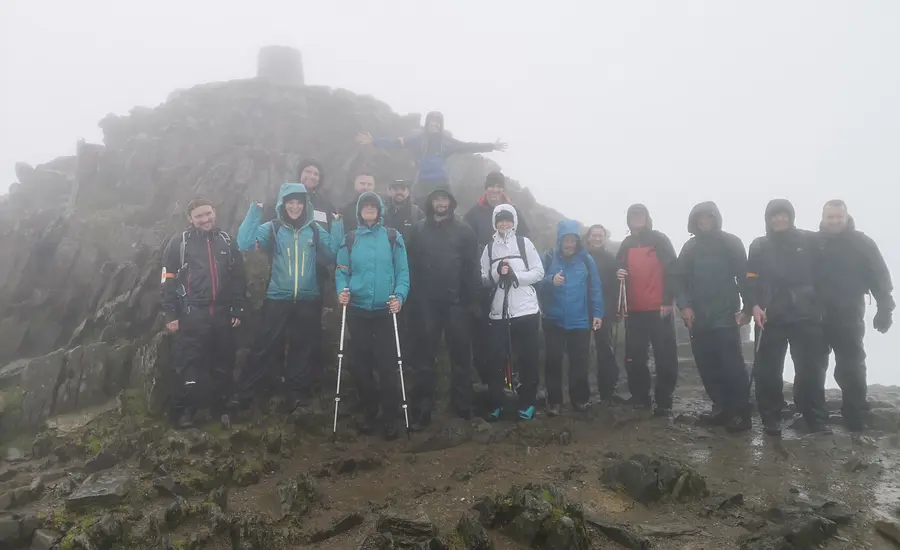 A group of people celebrate on top of a misty mountain