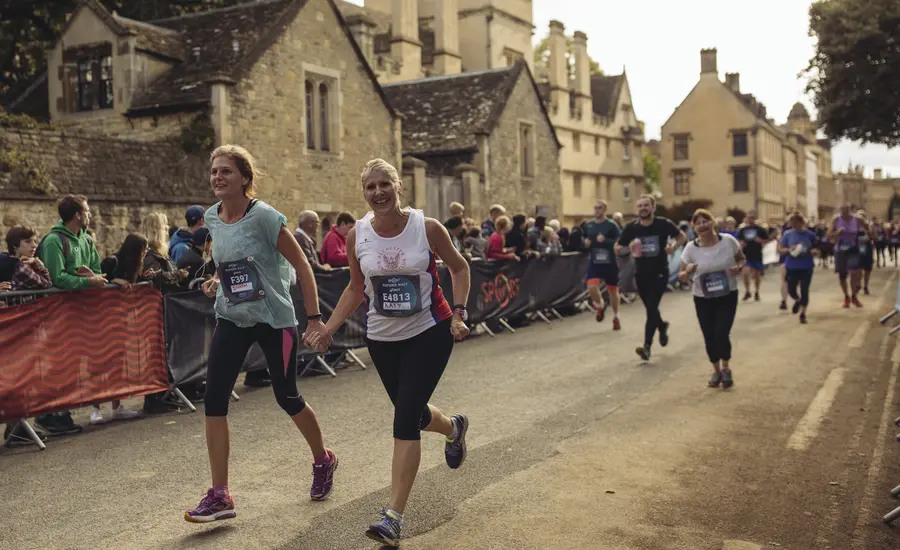Two women run down a street