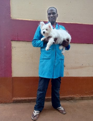 Dr Josphat stands holding a small white dog Dr Josphat stands holding a small white dog
