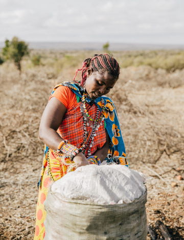 Kisima stands with a sack of charcoal Kisima stands with a sack of charcoal