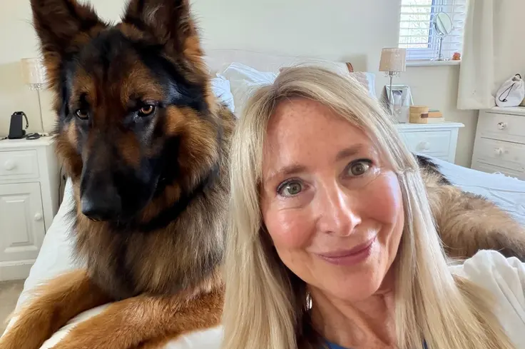 Klare Kennett, Brooke's Head of Brand Marketing and Communications, sits in a white room with Basil the Alsatian dog