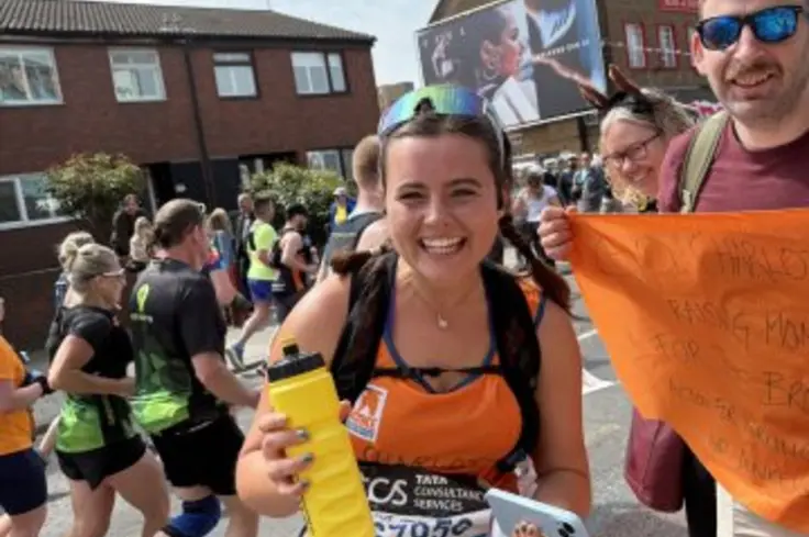 Charlotte Kitchen smiling at the camera as she stops during her run for Brooke at the London Marathon