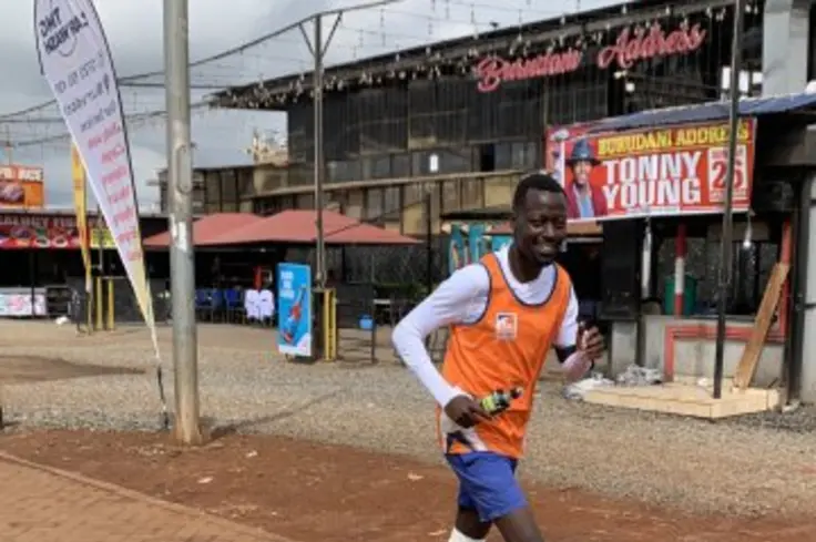 A man in an orange Brooke vest runs the MyWay Marathon in Kenya