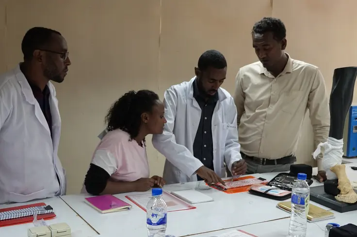 Faculty practicing their suturing with support from their peers 