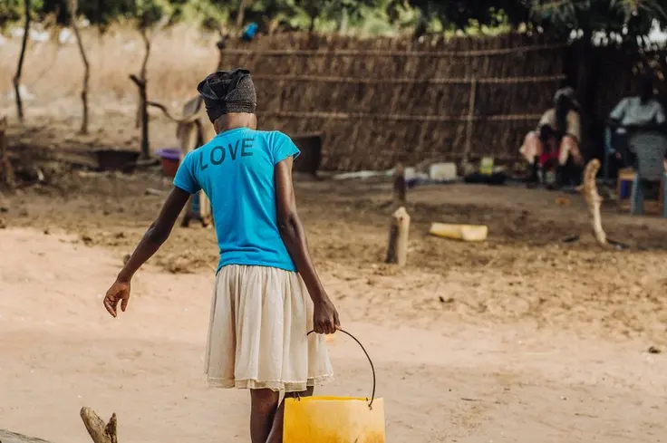 A girl carries a bucket of water in Senegal