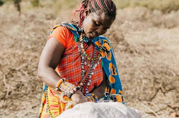 Kisima stands with a sack of charcoal